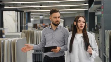 Porselen ya da seramik seramik seramik gibi yeni malzemeler seçen genç bir kadına bir nalbur dükkanındaki yenileme projesi için yardım eden profesyonel bir erkek danışman.