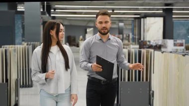 Profesyonel danışman, seramik zemin ve duvar kiremitlerini seçmesine yardım ederek, bir hırdavatçı dükkanında genç bir kadına yardım ediyor.