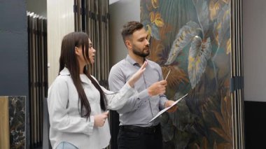 Genç bayan tasarımcı ve müşterisi çiçek desenli geniş format porselen taş yazılımını tartışıyorlar. Modern bir hırdavatçıda ev yenileme projesi için malzeme seçiyorlar.