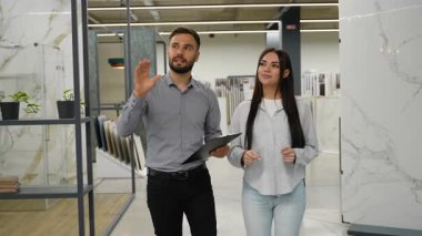 Erkek danışman ve bir bayan müşteri, ev yenileme için seramik seramik seramik seçimleri tartışıyorlar. Yönetici, müşteriye iç tasarım seçenekleri konusunda danışmanlık yapıyor.