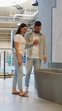 Mutlu genç çift banyolarını yenilemek için yeni bir banyo küveti ve fayanslar seçip tartışırken aynı zamanda büyük bir mağazada alışveriş yapıyorlar.