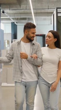 Mutlu çift, yeni apartman yenileme projeleri için seramik fayanslar ve döşeme seçeneklerini tartışarak ve seçerek ev geliştirme mağazasında kol kola yürüyor.