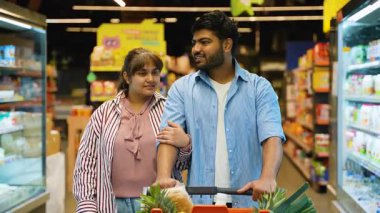 Mutlu Hintli çift süpermarket koridorlarında yürürken, taze ürünlerle dolu bir alışveriş arabasını iterken, raflardaki ürünlere bakarken, birlikte geçirdikleri zamanın tadını çıkarırken,