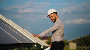 Bir elektrik santralinde güneş panellerini incelerken kasklı dans eden ve başarıyı kutlayan mutlu erkek mühendis..