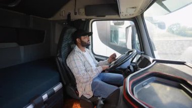 Modern bir kamyonet kabininde oturan deneyimli bir şoför motoru çalıştırmak için anahtarı kontağa çeviriyor ve ülke genelinde uzun mesafe teslimat yolculuğuna hazırlanıyor.