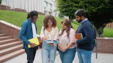 Çok uluslu bir grup öğrenci kampüs merdivenlerinde durmuş ödevlerini tartışıyor ve birlikte ders kitabı okuyorlar. Bir proje üzerinde çalışan ve sınavlara hazırlanan zeki gençler.