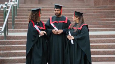 Üniversite merdivenlerinde duran üç yüksek lisans öğrencisinden oluşan çok ırklı bir grup. Mezuniyet töreninden sonra diplomalarını alıp kampüsün önünde konuşuyorlar.