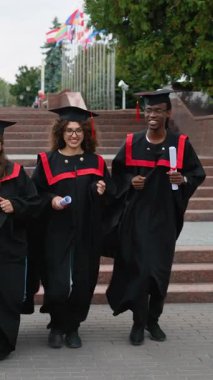 Geleneksel cübbe ve şapkalarla çeşitli üniversite mezunları açık havada yürüyorlar, akademik başarılarını kutluyorlar ve diplomalarını gururla taşıyorlar.