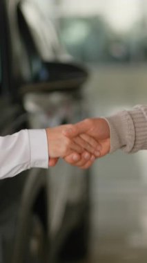 Bir satıcı ve bir müşterinin el sıkışarak satış şirketinde başarılı bir araba satışı anlaşması yapması, güveni sembolize etmesi ve yeni bir otomobil alımı için nihai anlaşmayı simgeliyor.