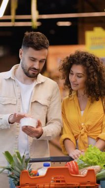 Marketten ürün seçen neşeli bir çift. Bir adam konteynırı tutuyor ve alışveriş yaparken kız arkadaşıyla tartışıyor.