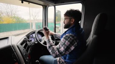 Yarı kamyon kullanan ve telsizle konuşan profesyonel bir erkek kamyoncu. Lojistiği yolda koordine eden kamyon şoförü.