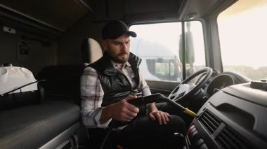 Kamyon kulübesinin içini koruyan profesyonel bir şoför. Çalışkan erkek işçi torpido gözünü ve direksiyonu buharlı temizleyici kullanarak temizliyor.