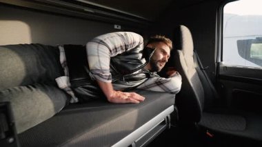 Uzun yol şöförü kamyonetlerinin içinde uykusundan uyanmış. Profesyonel kamyoncu yolculuğuna devam etmeden önce dinleniyor.