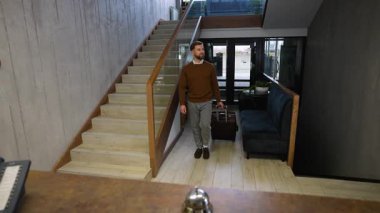 Bavullu genç bir erkek misafir modern bir otele geliyor. Gülümseyen adam servis zilini çalar ve kayıt için resepsiyonistle konuşur.