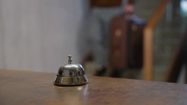 Otel servis zilini kapat. Bir bavulla gelen erkek turist resepsiyona yaklaşıyor ve servis için zili çalıyor.