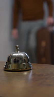 Tanımlanamayan bir misafir otele geliyor, yardım çağırmak için ahşap resepsiyondaki parlak gümüş servis zilini çalıyor.