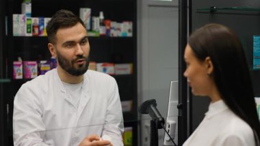Kadın bir hastaya danışan profesyonel bir erkek eczacı. Bir müşteriye uyuşturucu tedavisi ve sağlık hizmetleri hakkında danışmanlık yapan yardımsever bir kimyager
