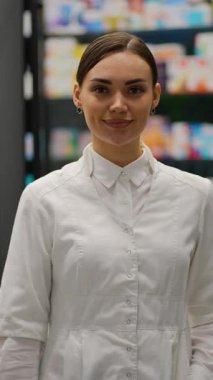 Beyaz bir ilaç şişesi tutarken gülümseyen ve kameraya bakan pozitif kadın eczacı. Profesyonel sağlık hizmeti kavramı