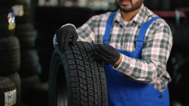 Bir atölyedeki otomotiv teknisyeni, yeni bir kış lastiğinin lastik izini ölçmek için derinlik göstergesi kullanarak güvenlik ve kalite kontrolü sağlıyor.