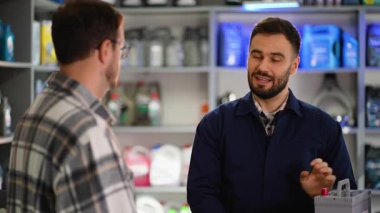 Uzman bir oto hizmet çalışanı, bir erkek müşteriye özel bir mağazada araba parçası seçmesinde yardım ediyor. Profesyonel tamirci araç aksesuarları satıyor.