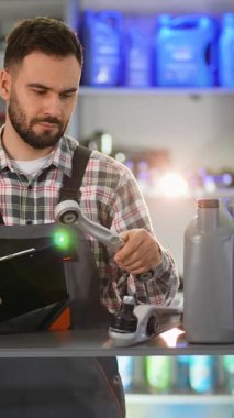 Otomotiv yedek parçalarını inceleyen profesyonel araba tamircisi ve benzin istasyonunun deposundaki bir panoya notlar yazıyor.