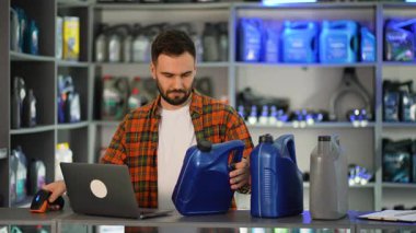 Otomobil parçalarında çalışan genç bir erkek barkodları motor yağı kutularında tarıyor ve bilgileri bir dizüstü bilgisayara giriyordu.