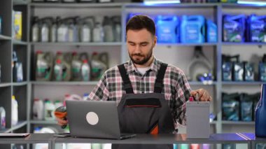 Yeni bir araba aküsünde barkod tarayıcısı kullanarak bir oto yedek parça dükkanında profesyonel bir erkek işçi.