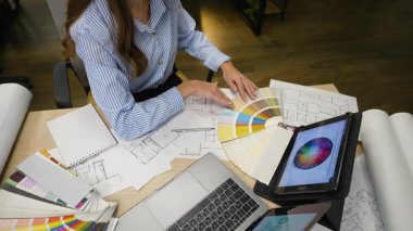 Masasında çalışan profesyonel iç mimar paletten renkler seçiyor ve yeni bir konut projesi için tablet kullanıyor.