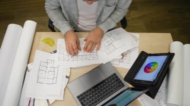 Bir konut projesinde çalışan erkek tasarımcıların üst görüntüsü. Mimari bir plan çizer ve iç mekan için renk seçer