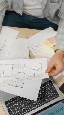 Masasında yeni bir proje üzerinde çalışırken kat planlarını ve renk örneklerini inceleyen bir erkek mimarın ya da iç tasarımcının en alttaki görüntüsü