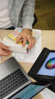 Profesyonel iç mimar ya da tasarımcı bir masada çalışıyor, kumaş yelpazesinden renkler seçiyor ve yeni bir proje için tablet kullanıyor