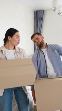 Genç evli çift ağır karton kutular taşırken yorgun hissediyorlar. Yer değiştirme işlemi sırasında sırt ağrısı çeken bir adam.