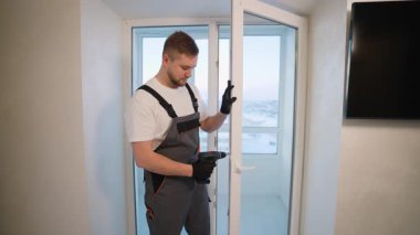 Profesyonel tamirci plastik balkon kapısını tamir etmek için kablosuz tornavida kullanıyor. Ev yenileme ve bakım hizmeti