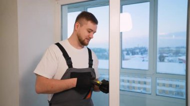 Yeni bir apartman dairesine plastik pencere ya da balkon kapısını ayarlamak için tornavida kullanan işçi.