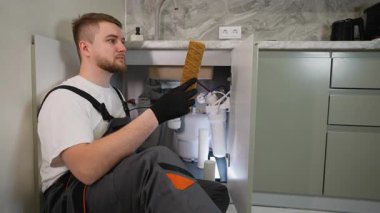 Profesyonel tesisatçı, kirli ve kullanılmış bir su filtresi kartuşunu gösteriyor. Genç teknisyen ters osmoz sistemine hizmet veriyor.