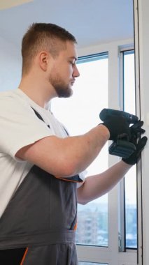 Modern bir daireye yeni bir plastik pencere takmak için kablosuz elektrikli tornavida kullanan profesyonel beyaz işçi.