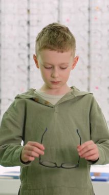 Yakışıklı küçük çocuk gözlüğünü ilk kez bir gözlükçünün kliniğinde takıyor. Gülümsüyor, seçimiyle mutlu.