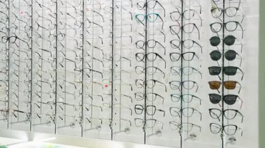 Gözlükçünün dükkanındaki parlak bir ekranda geniş bir gözlük ve güneş gözlüğü seçimi. Modern görüş giysisinin geniş çeşitliliği