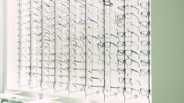 Modern bir optik mağazada geniş bir gözlük ve çerçeve seçimi sergilenmektedir. Görüş düzeltmesi ve moda için göz giyimi seçenekleri