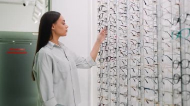 Gözlükçüden yeni gözlük seçen güzel bir genç kadın. Gözlükleri için yeni bir çerçeve deneyen bir bayan müşteri.