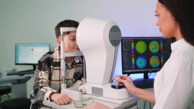Bir göz doktorunda modern bir kornea topografı kullanan genç bir hasta üzerinde kapsamlı bir göz muayenesi yapan kadın optometrist.