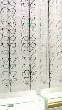 Büyük bir gözlük ve güneş gözlüğü çeşidiyle gösteri odası. Modern bir optik mağazasında vizyon düzeltmesi için satılık şık çerçeveler