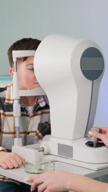Klinikteki modern tanı ekipmanlarını kullanarak çocuk vizyonunu kontrol eden profesyonel bir göz doktoru. Dikkatli göz bakımı ve sağlık kontrolü