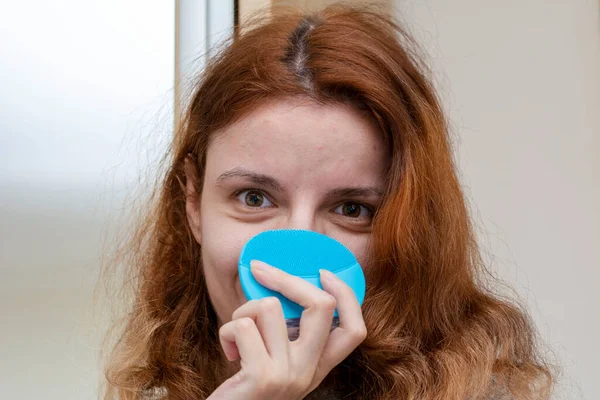 Mujer Cabeza Roja Usando Cepillo Limpieza Facial Para Una Rutina Imagen de stock