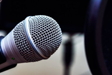 Bir pop filtresiyle korunan bir mikrofona yaklaş.