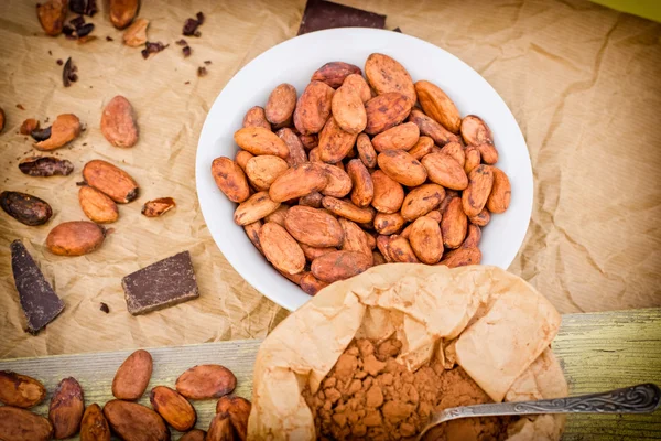 Fèves de cacao, cacao en poudre et chocolat noir sur la table — Photo