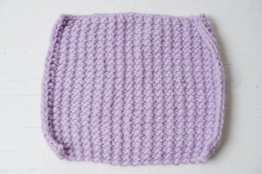 Beyaz arka planda ev konforu üzerine eflatun örülmüş el yapımı battaniye.