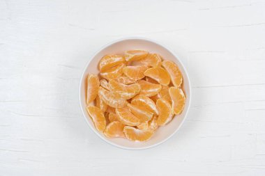 Mandalina dilimleri arka planda beyaz tabakta