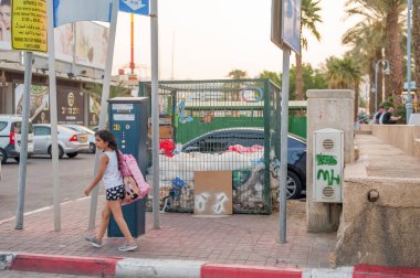 Bir kız geri dönüşüm gecesi için çöp konteynırının önünden geçiyor.