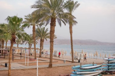 Akşam otellerinde yürüyen insanların gün batımında plaj kafeleri satın aldığı turistik alan manzarası